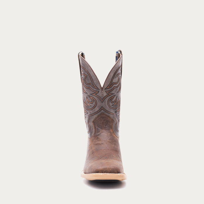 Brown cowboy boot with tan and black intricate stitching on a light gray background