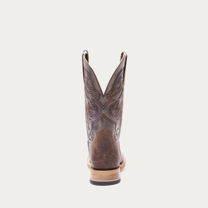 Brown cowboy boot with tan and black intricate stitching on a light gray background