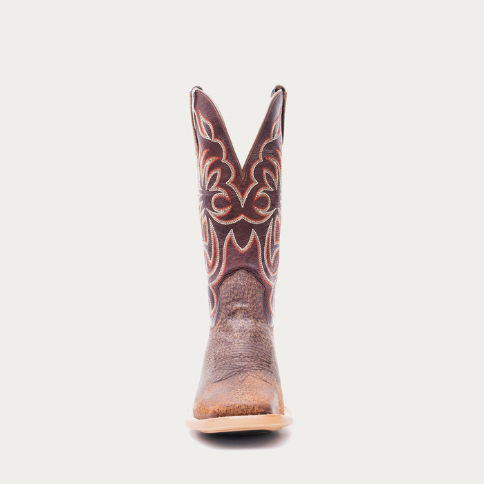 Brown cowboy boot with white and red intricate stitching on a light gray background