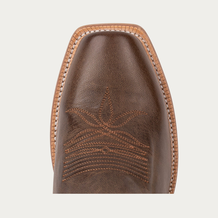 Close-up of a brown leather boot sole with intricate stitching on a light gray background