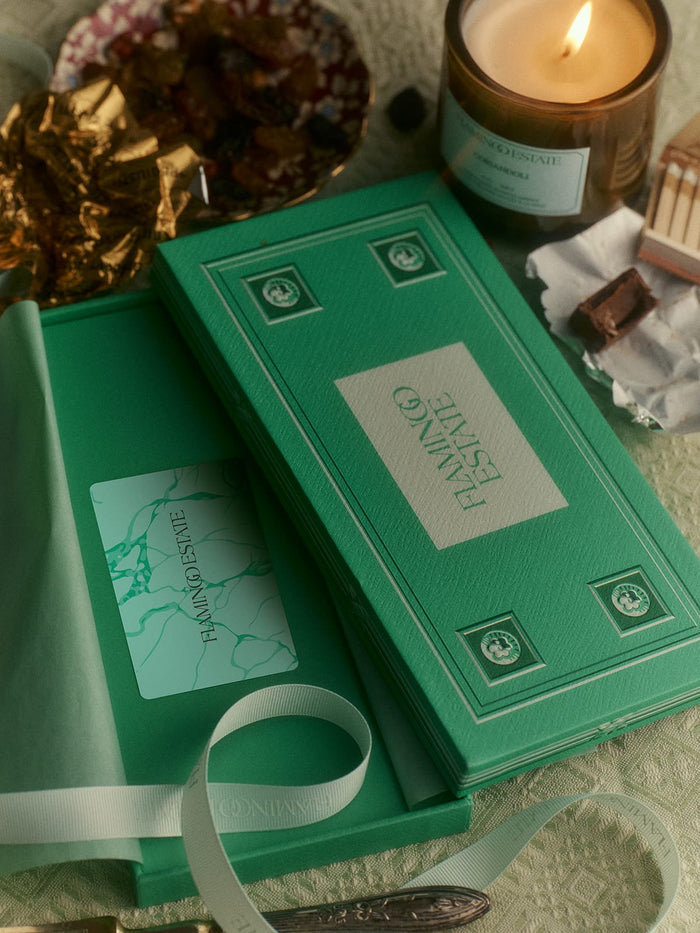 Box labeled "Flamingo Estate" holds a card alongside a burning candle.