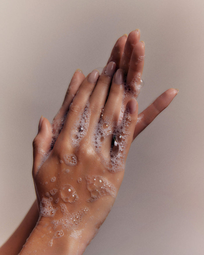 Hands covered in foamy soap rub together, cleaning.