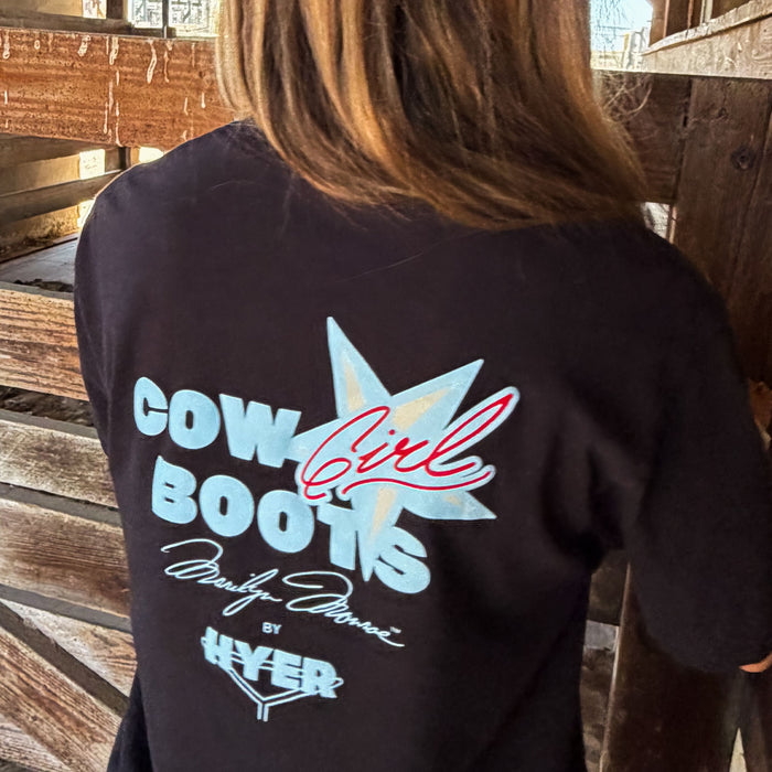 Black t-shirt with 'Cow Girl Boots' design on the back, worn by a person in a wooden setting.