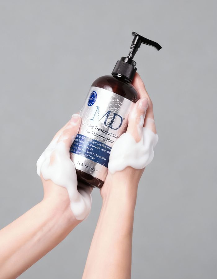 Hand holding MD® Revitalizing Treatment Shampoo bottle – sulfate-free peptide formula for fuller-looking hair and scalp care, from the MD Hair system