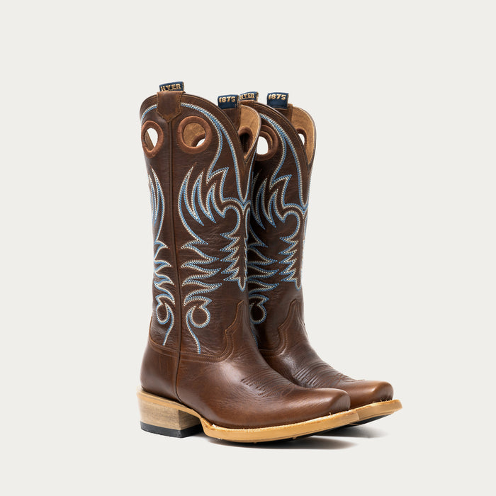 Pair of brown cowboy boots with intricate white and blue embroidery on a light gray background