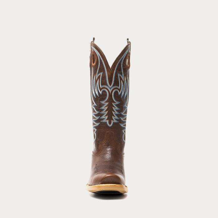 Brown cowboy boot with intricate white and blue stitching on a light gray background