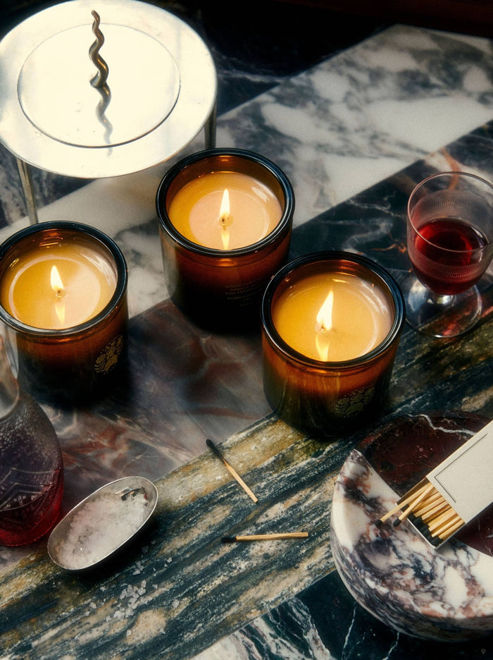 Lit Flamingo Estate Candle On A Marble Surface With A Box Of Matches