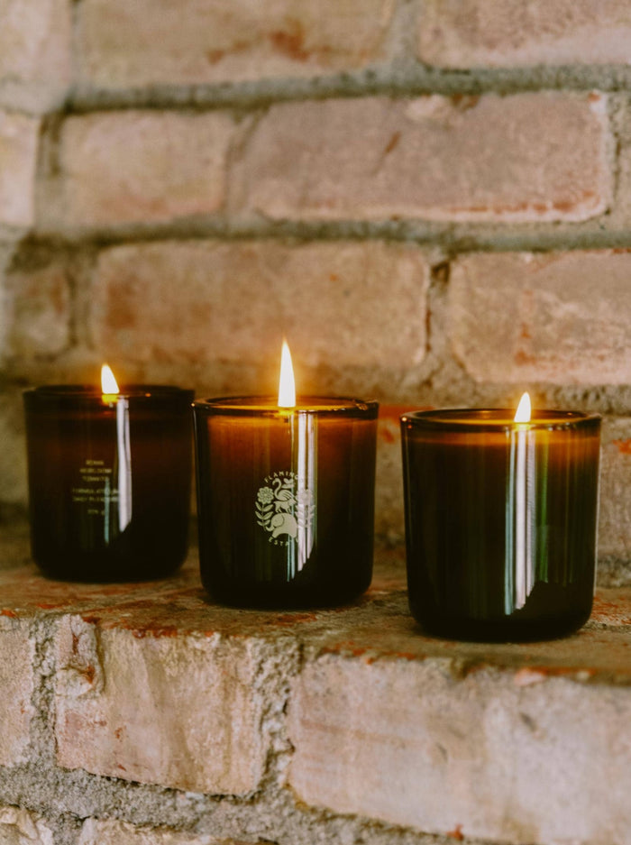 Three Lit Candles On A Brick Wall