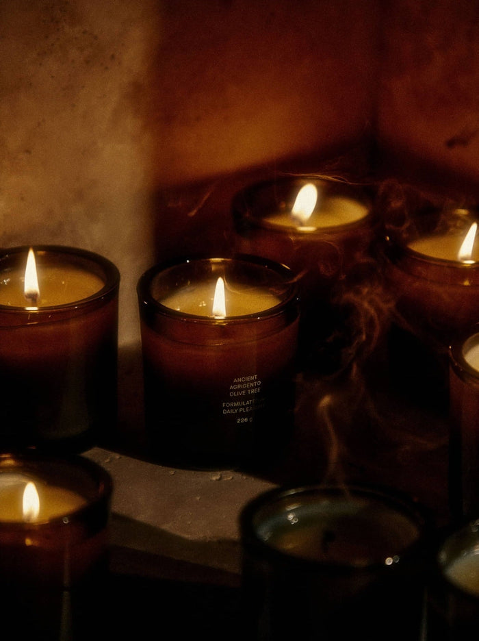 Candles flicker in dim light, releasing wisps of smoke.