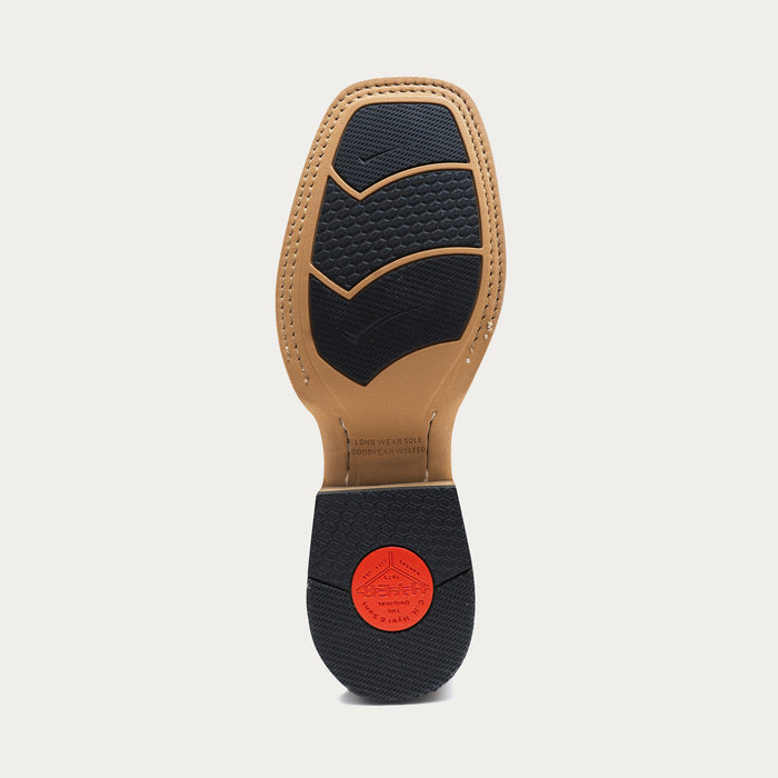 Close-up of a tan shoe sole with black rubber insets and a red heel cap on a light gray background