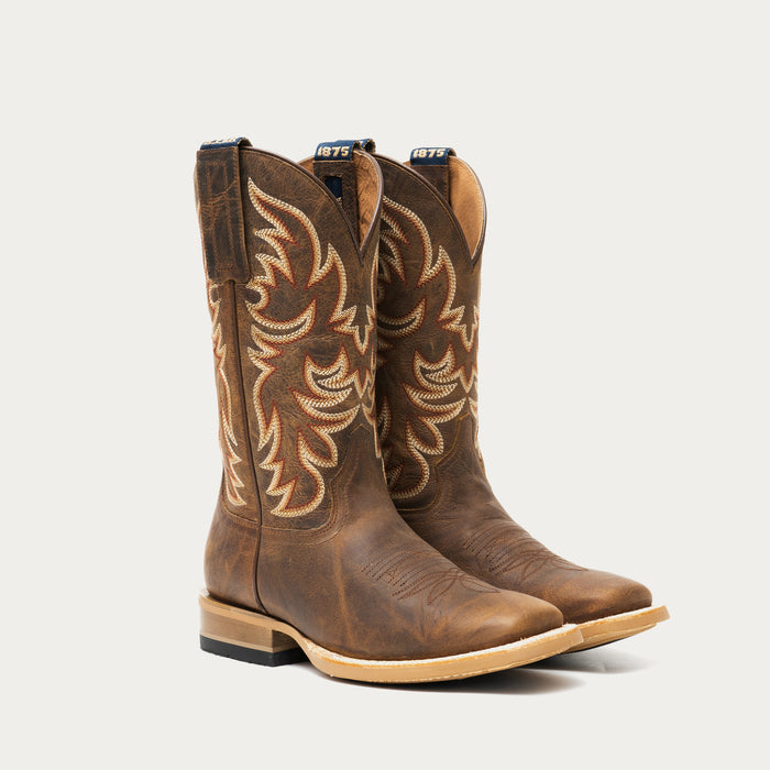 Pair of brown cowboy boots with intricate designs on a light gray background